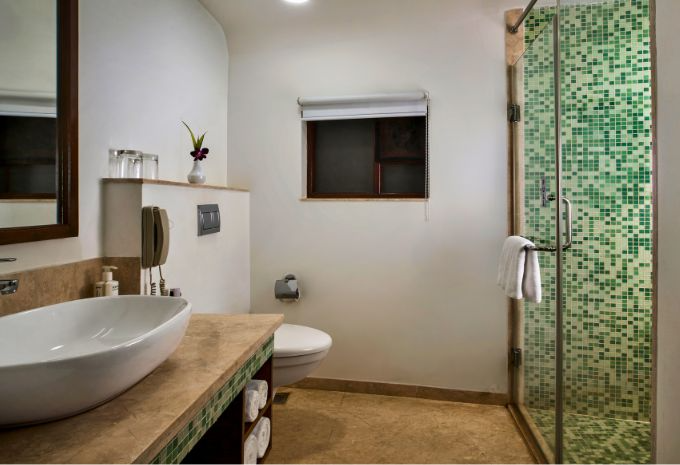 Bathroom with green mosaic tile glass shower and stone vanity at Mercure Goa Devaaya Resort