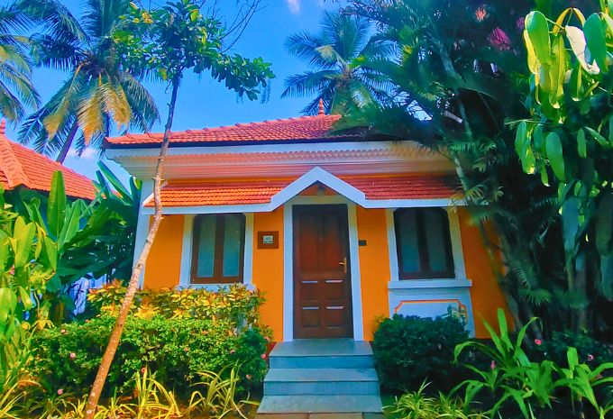 Freestanding orange villa with terracotta roof and tropical garden at Mercure Goa Devaaya Resort Divar Island